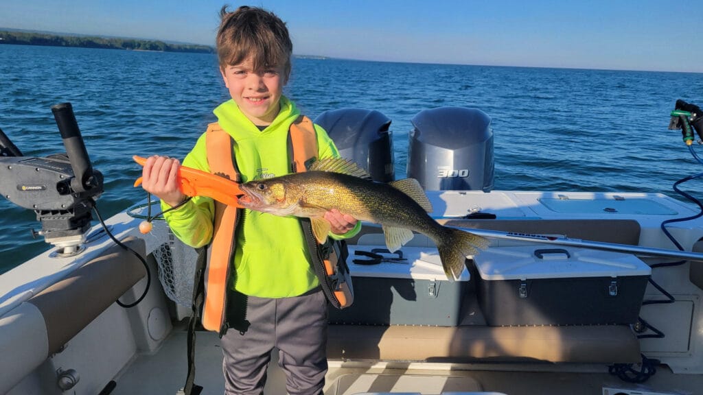 Youngster on boat holding a walleye caught on Lake Erie