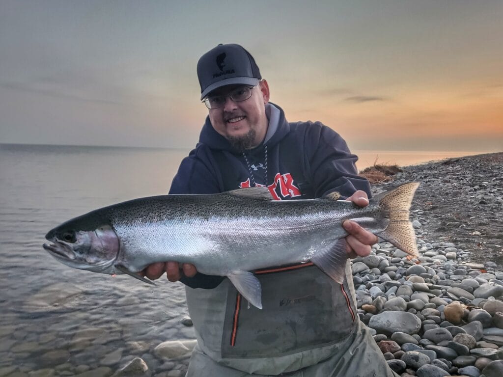 fisherman at edge of Lake Erie shore with a trophy steelhead 